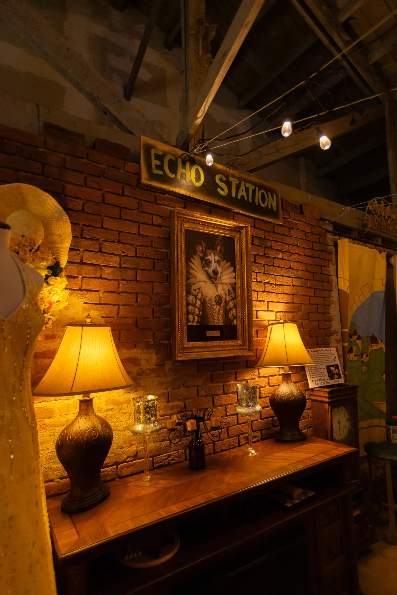 A Renaissance-style oil portrait of Echo the dog in a ruff collar, framed in gold on the exposed brick wall beneath a vintage Echo Station sign