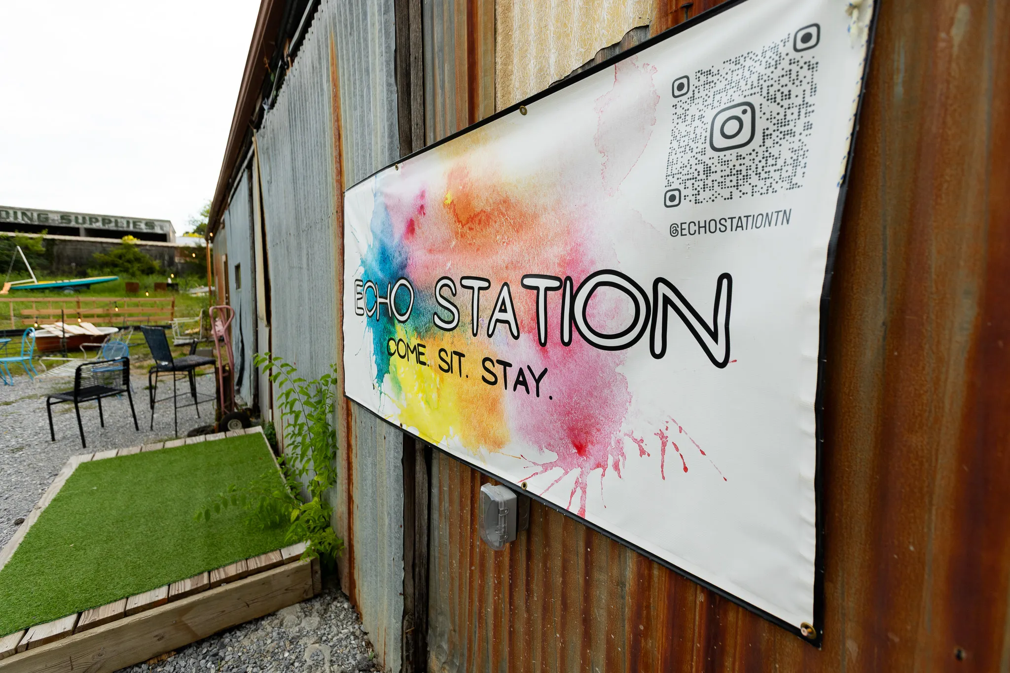 The Echo Station banner on rusted corrugated siding, beside the gravel patio and outdoor seating